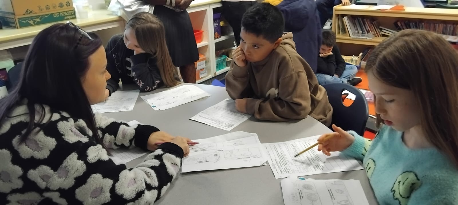 A group of students sit around a table. 